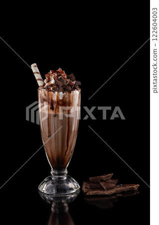 Closeup glass of chocolate milkshake decorated with caramel and whipped cream isolated at black background. 122604003