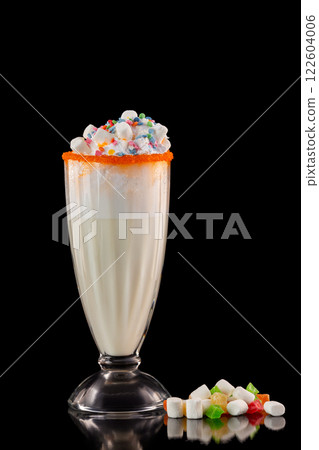 Glass of tasty sweet milkshake decorated with marshmallow isolated at black background. 122604006