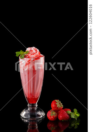Glass of fresh strawberry milkshake decorated with mint and syrup isolated at black background. Glass of fresh strawberry milkshake decorated with mint and syrup isolated at black background. 122604016