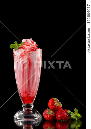 Glass of fresh strawberry milkshake decorated with mint and syrup isolated at black background. Glass of fresh strawberry milkshake decorated with mint and syrup isolated at black background. 122604017