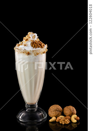 Glass of sweet milk cocktail with nuts isolated at black background. Glass of sweet milk cocktail with nuts isolated at black background. 122604018