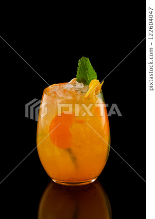 Closeup glass of orange tangerine fresh juice with ice cubes isolated at black background. Closeup glass of orange tangerine fresh juice with ice cubes isolated at black background. 122604047