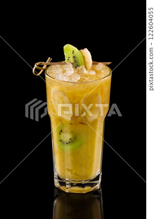 Closeup glass of fresh yellow banana smoothie with kiwi isolated at black background. 122604055