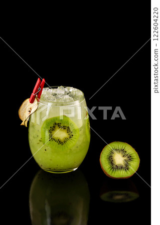 Closeup glass of healthy kiwi juice cocktail with ice isolated at black background. 122604220