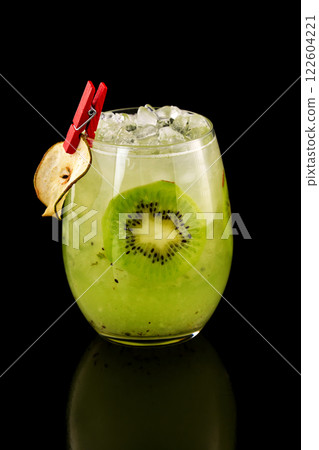 Closeup glass of healthy kiwi smoothie cocktail with ice isolated at black background. Closeup glass of healthy kiwi smoothie cocktail with ice isolated at black background. 122604221