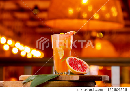 Glass of fresh orange juice with lemon, grapefruit and lime on a wooden board at orange blurred background. 122604226