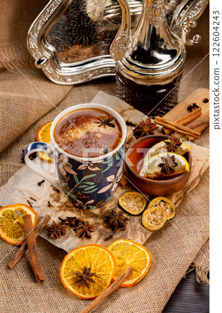 Closeup cup of turkish spiced coffee at decorated wooden table with orange chips, cennamon sticks and sack clothing background. Closeup cup of turkish spiced coffee at decorated wooden table with orange chips, cennamon sticks and sack clothing background. 122604243
