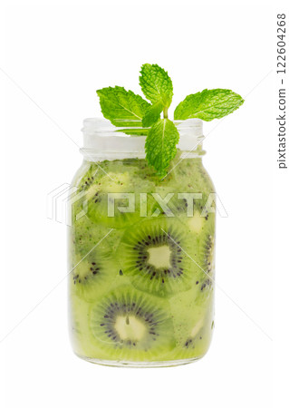 Closeup jar of kiwi fruit smoothie with slices of green kiwi served with mint isolated at white background. Concept of detox dieting and healthy lifestyle. Closeup jar of kiwi fruit smoothie with slices of green kiwi served with mint isolated at white background. Concept of detox dieting and healthy lifestyle. 122604268