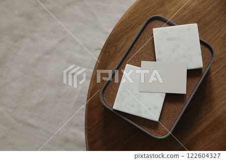 Blank business card and marble tiles mockups on round wooden coffee table. Blurred beige carpet. Elegant branding template. Flat lay, top view. Copy space. Moody still life, creativity concept 122604327