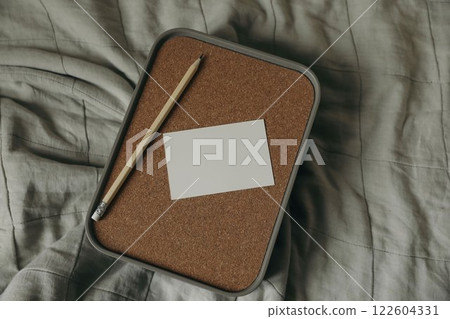Empty business card, invitation mockup, wooden pencil on storage container box, cork lid. Wrinkled beige cloth, throw. Elegant branding template. Flat lay, top view. Copy space. Moody still life. 122604331
