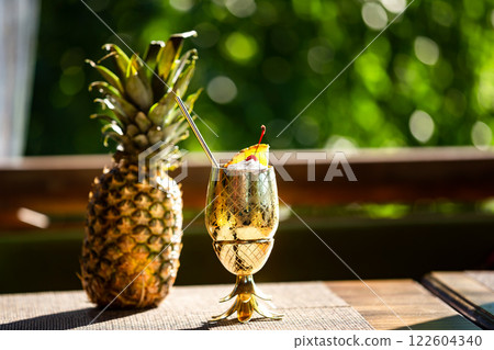 Closeup pina colada cocktail served in metal golden color glass and a pineapple fruit at green background. 122604340