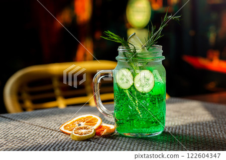Closeup jar of cucumber and tarragon lemonade served with orange chips at bar background. Closeup jar of cucumber and tarragon lemonade served with orange chips at bar background. 122604347
