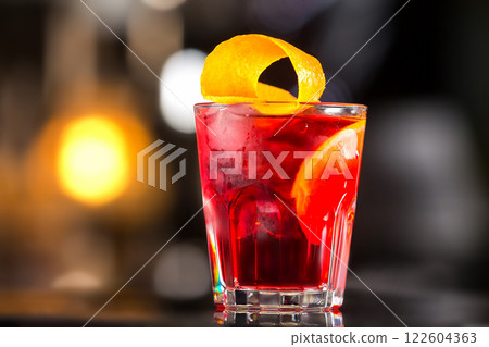 Closeup glass od red alcoholic cocktail decorated with lemon at bright bar stand background. 122604363