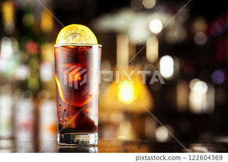 Rum cola casual cocktail with ice cubes and lemon at festive bar stand background. Rum cola casual cocktail with ice cubes and lemon at festive bar stand background. 122604369