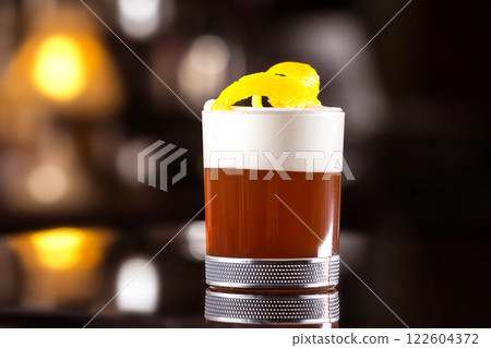 Closeup image of glass of cocktail decorated with cream and lemon at bar stand background. Closeup image of glass of cocktail decorated with cream and lemon at bar stand background. 122604372
