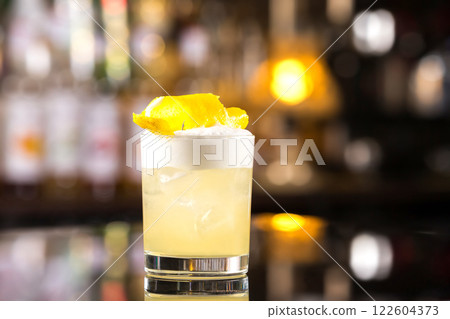 Closeup glass of whiskey sour cocktail decorated with lemon at bar background. Closeup glass of whiskey sour cocktail decorated with lemon at bar background. 122604373