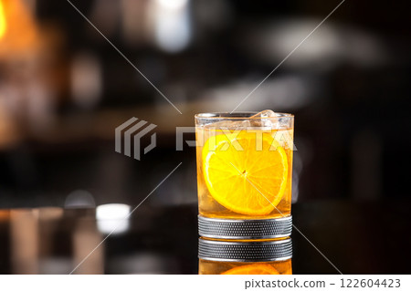 Closeup glass of godfather cocktail with slice of orange and ice cubes at bright bar background. Closeup glass of godfather cocktail with slice of orange and ice cubes at bright bar background. 122604423