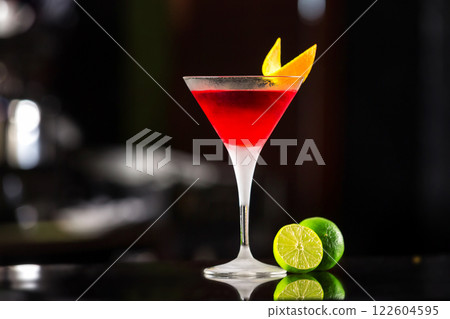 Closeup glass of cosmopolitan cocktail decorated with orange at bar background. Closeup glass of cosmopolitan cocktail decorated with orange at bar background. 122604595
