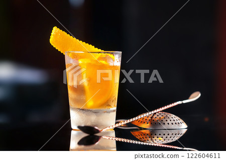 Closeup glass of old fashioned cocktail decorated with orange at bar counter background. 122604611