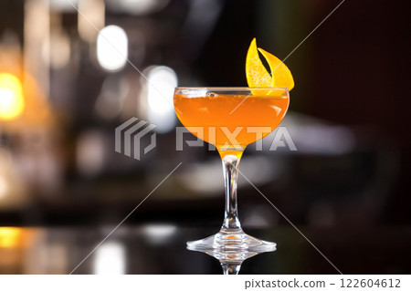 Glass of sidecar orange cocktail decorated with lemon at bar counter background. Glass of sidecar orange cocktail decorated with lemon at bar counter background. 122604612