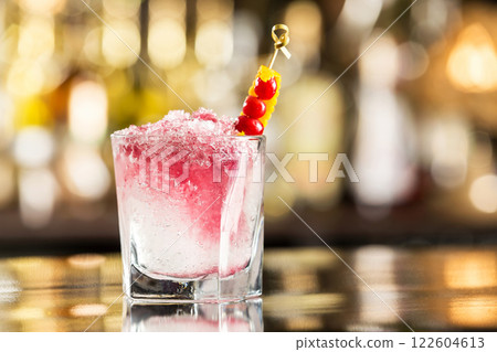 Glass of shirley temple cocktail decorated with cherry and frappe at bar counter. Glass of shirley temple cocktail decorated with cherry and frappe at bar counter. 122604613