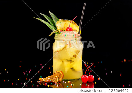 Fresh pineapple cocktail in jar decorated with cherry and colorful candies isolated at black background. Fresh pineapple cocktail in jar decorated with cherry and colorful candies isolated at black background. 122604632