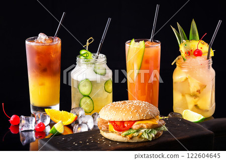 Group of fresh summer cocktails and burger at wooden board isolated at black background. 122604645