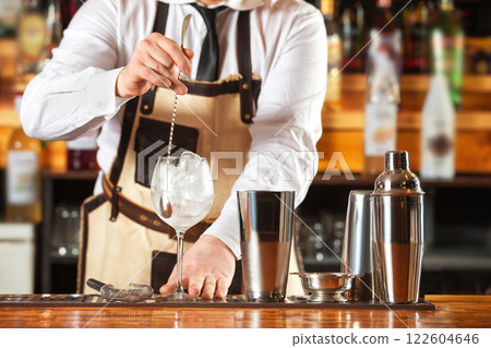 Bartender is mixing cocktail with spoon at bar counter background. 122604646