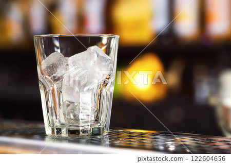 Closeup image of glass with ice cubes at bright bar counter background. 122604656