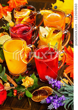 Vertical iimage of glasses set with different colorful natural hot tea decorated with autumn leaves at wooden dark board background. Vertical iimage of glasses set with different colorful natural hot tea decorated with autumn leaves at wooden dark board background. 122604660