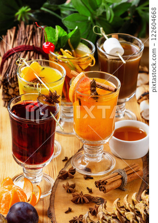 Verical image of hot drinks group of mulled wine glasses and teas served with fruits at decorated wooden holiday table background. Verical image of hot drinks group of mulled wine glasses and teas served with fruits at decorated wooden holiday table background. 122604668