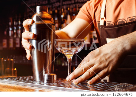 Male bartender is making cocktail holding shaker at bar background. 122604675