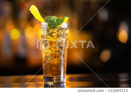 Closeup glass of long island ice tea cocktail decorated with mint at bar counter background. Closeup glass of long island ice tea cocktail decorated with mint at bar counter background. 122604723