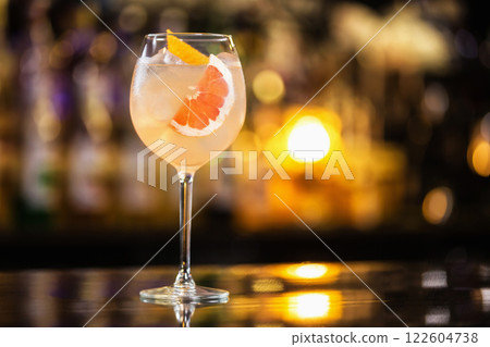Closeup glass of sparkling wine cocktail decorated with grapefruit at bar counter background. 122604738