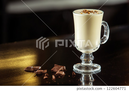 Glass of milk cocktail decorated with chocolate at table background. Glass of milk cocktail decorated with chocolate at table background. 122604771
