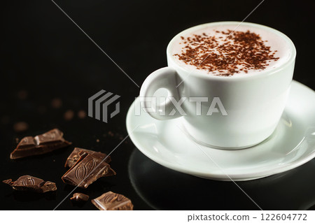 Closeup image of white cup full of hot chocolate with milk at dark background. Closeup image of white cup full of hot chocolate with milk at dark background. 122604772