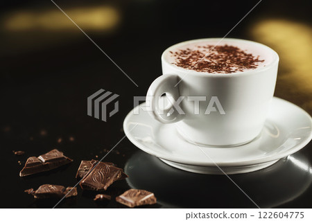 Closeup image of white cup full of latte coffee at dark background. Closeup image of white cup full of latte coffee at dark background. 122604775