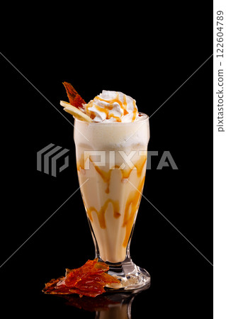 Closeup glass of caramel milk shake isolated at black background. Closeup glass of caramel milk shake isolated at black background. 122604789