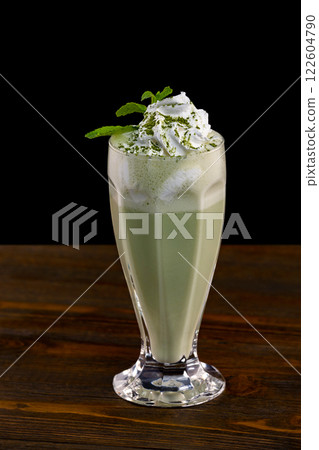 Closeup glass of mint milk shake decorated with whipped cream isolated at black background. Closeup glass of mint milk shake decorated with whipped cream isolated at black background. 122604790