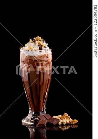 Closeup glass of chocolate milk shake with nuts decorated with whipped cream isolated at black background. 122604792