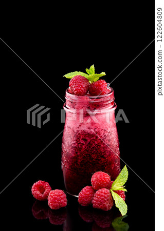 Closeup jar of fresh raspberry smoothie decorated with mint isolated at black background. 122604809