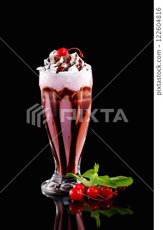 Closeup vertical glass of cherry with cholocate milkshake decorated with mint isolated at black background. Closeup vertical glass of cherry with cholocate milkshake decorated with mint isolated at black background. 122604816