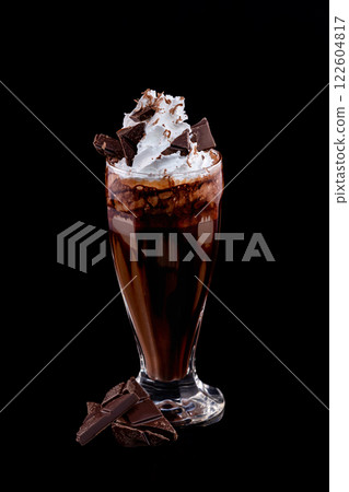 Closeup vertical glass of chocolate milkshake decorated with whipped milk isolated at black background. Closeup vertical glass of chocolate milkshake decorated with whipped milk isolated at black background. 122604817