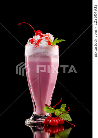 Closeup glass of cherry milk shake decorated with mint and berries isolated at black background. Closeup glass of cherry milk shake decorated with mint and berries isolated at black background. 122604932