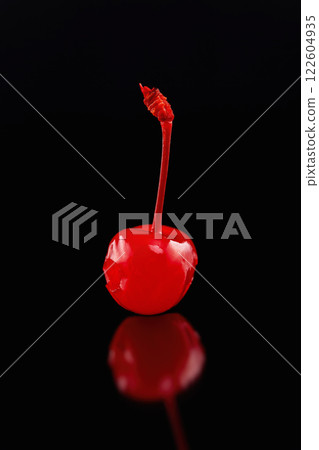 Macro image of single cocktail cherry with reflection isolated at black background. 122604935