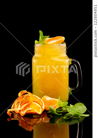 Closeup jar of fresh orange juice decorated with mint isolated at black background. 122604951