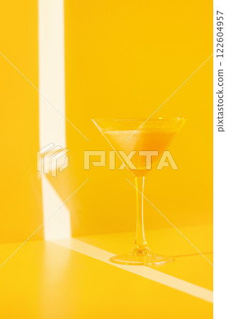 Closeup glass of banana cocktail at yellow minimal background with light stripes. Closeup glass of banana cocktail at yellow minimal background with light stripes. 122604957