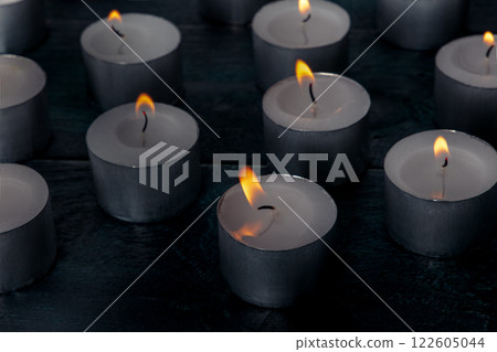 Tea light candles on a dark background, many lights in the dark Tea light candles on a dark background, many lights in the dark 122605044