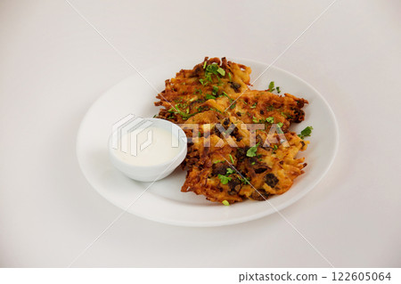 Fried brown potato pancakes with cup of cream on a plate isolated at white background. Traditional Russian meal. 122605064