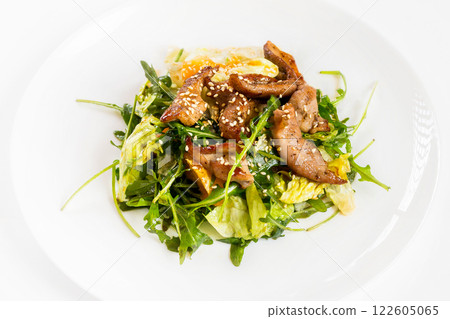 Closeup image of roasted duck at plate with green salad isolated at white background. Closeup image of roasted duck at plate with green salad isolated at white background. 122605065